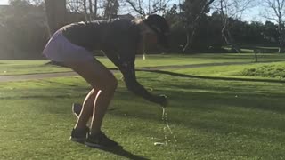 Girl shotgunning beer while playing golf