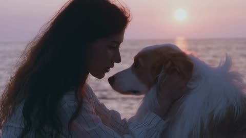 portrait Lonely brunette woman kissing with her dog at the beach at sunset