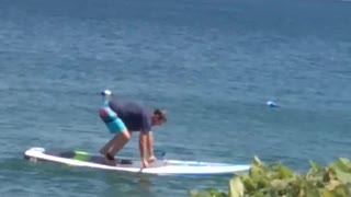 Man Struggles with Lakeside Paddleboard