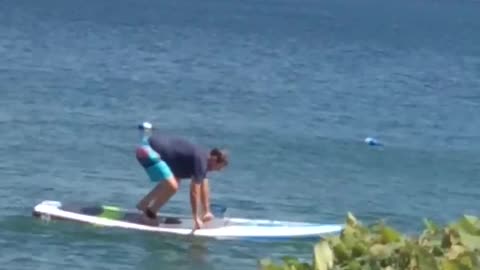 Man Struggles with Lakeside Paddleboard