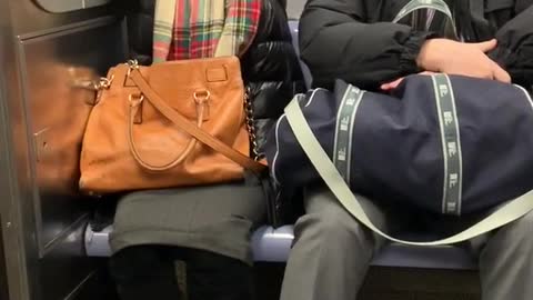 Woman wearing plaid scarf on a subway sleeping and flailing her hands up and down