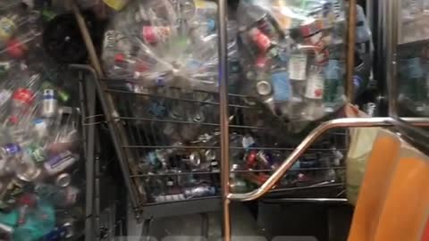 Subway train filled with dozens of bags and shopping cart full of aluminum soda cans